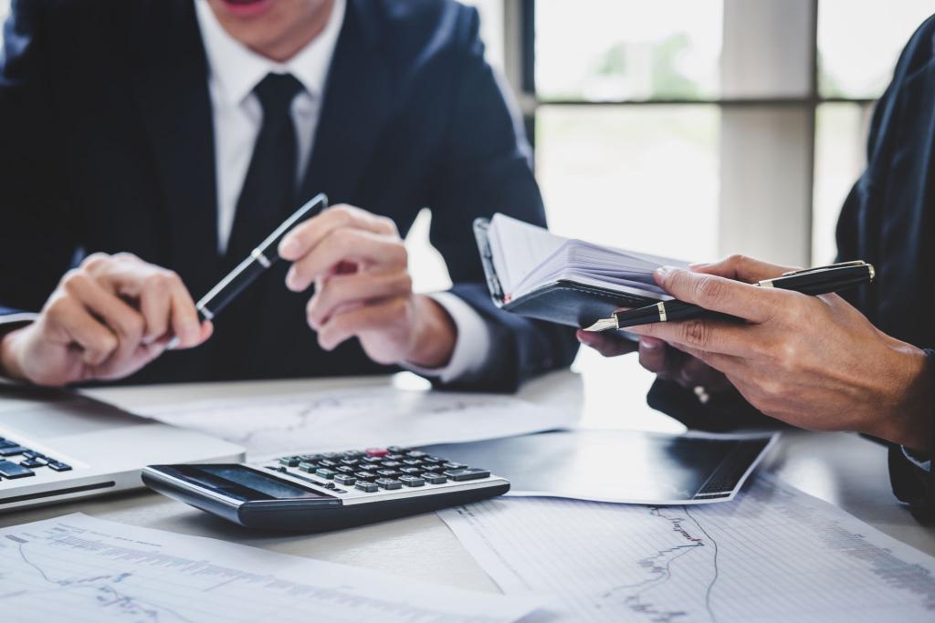 Professional advisers reviewing financial documents and calculator on desk