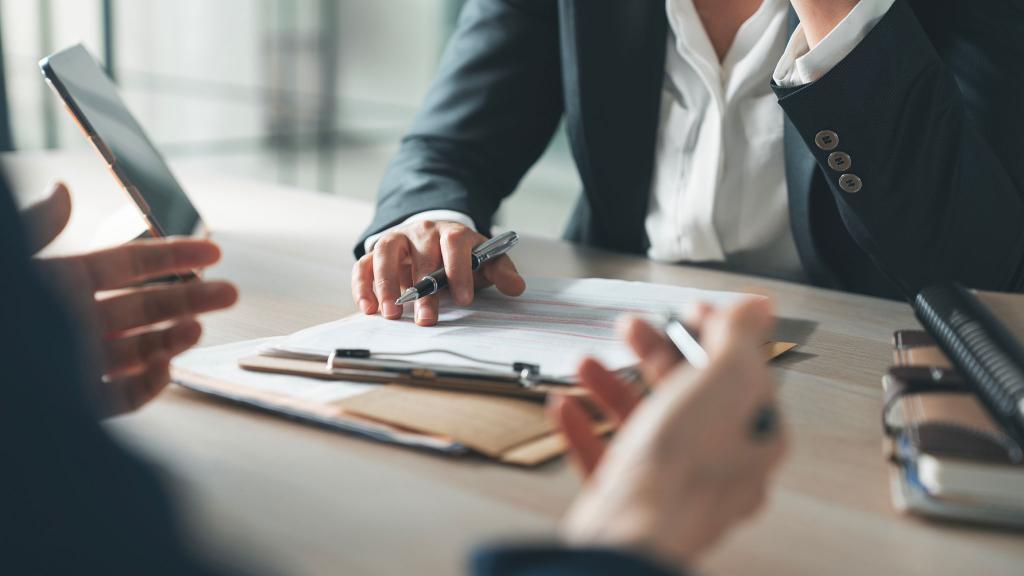 Professional reviewing signed documents on clipboard in a business meeting